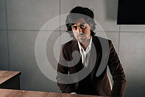 Portrait of successful confident businessman looking at camera with serious expression sitting at office desk. Front