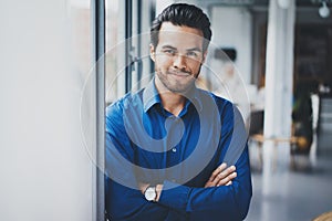 Portrait of successful confident hispanic businessman smiling and standing close from the window in modern office