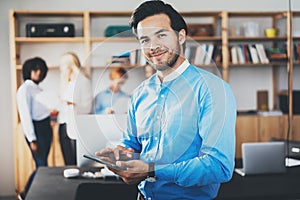 Portrait of successful confident hispanic businessman using tablet in hands and looking at the camera in modern office