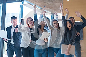 Portrait of successful creative business team looking at camera and celebrating. Diverse business people standing together at