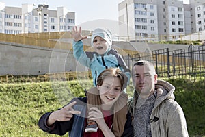 A portrait of a successful dad, a young teenager and a happy little son on his brother's shoulders