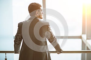 Portrait of a successful handsome businessman in front of a window, there is an empty space for text