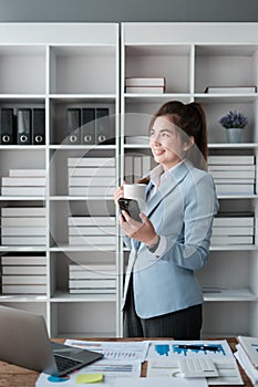 Portrait of a successful and happy businesswoman in her office, an office worker smiling and looking at the window with