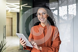 Portrait of successful hispanic woman inside office at workplace, businesswoman smiling and looking at camera, female