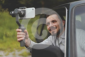 Portrait of successful man recording video at smartphone with steadycam