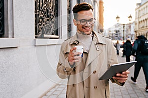 Portrait of a successful man using digital tablet during quick break in urban background