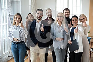 Portrait of successful mature businesswoman and team showing thumbs up