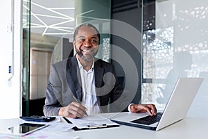 Portrait of successful mature experienced financier, business man behind paper work smiling and looking at camera