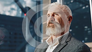 Portrait of Successful Middle Aged Businessman in a Suit Riding Glass Elevator to Office in Modern