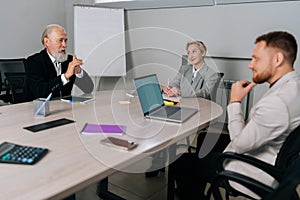 Portrait of successful middle-aged businesswoman attending meeting with diverse-ages colleagues in office. Experienced