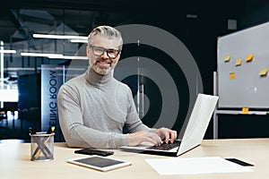 Portrait of successful senior businessman, gray haired man in glasses smiling and looking at camera, mature investor