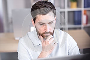 Portrait of a successful and serious businessman, pensive man looking at the camera working in the office at the computer