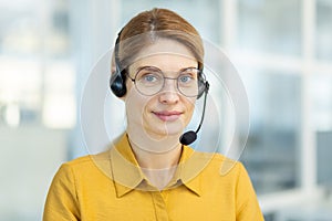 Portrait of successful smiling business woman with headset phone, mature experienced worker smiling and looking at