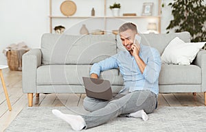 Portrait of successful smiling businessman using phone and pc