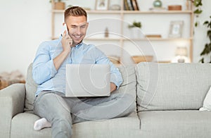Portrait of successful smiling guy using phone and pc