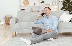 Portrait of successful smiling man using phone and laptop