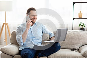 Portrait of successful smiling worker using phone and pc