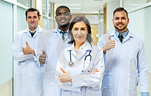 Portrait of successful team of medical doctors are looking at camera and smiling while standing in hospital