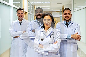 Portrait of successful team of medical doctors are looking at camera and smiling while standing in hospital