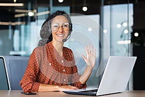 Portrait of successful tech support worker, hispanic woman with curly hair smiling and looking at camera, businesswoman