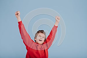 Portrait of successful teen boy winner with raised hands