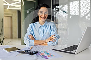 Portrait of successful young businesswoman, Hispanic woman working inside modern office building smiling and looking at