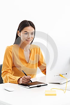 Portrait of successful young designer woman using graphic tablet computer and stylus pen in bright office