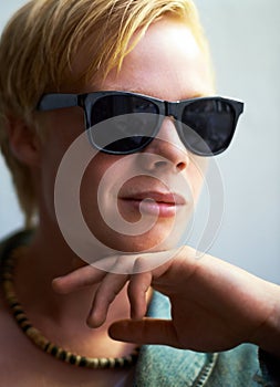 Portrait, sunglasses and a cool young boy in studio on a gray background for trendy youth fashion. Face, kids and