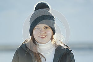 Portrait sunlit teenage girl wearing winter clothes in winter outside