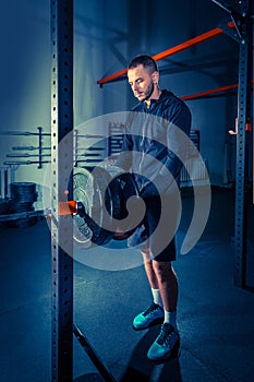 Portrait of super fit muscular young man working out in gym with barbell