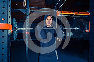 Portrait of super fit muscular young man working out in gym with barbell