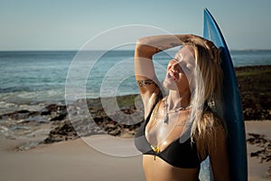 Portrait of surfer girl with surfboard at the beach. Close up. Surfer girl enjoying sunshine. Tegal Wangi beach, Bali, Indonesia