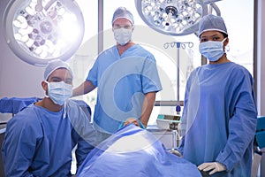 Portrait of surgeon with patient lying on bed in operation room