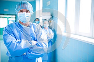 Portrait of surgeon standing with arms crossed in corridor