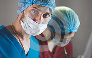 Portrait of surgeons at work, operating in uniform, looking at camera.