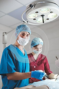Portrait of surgeons at work, operating in uniform, looking at camera.