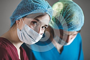 Portrait of surgeons at work, operating in uniform, looking at camera.