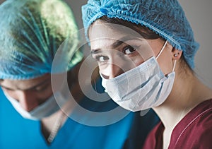 Portrait of surgeons at work, operating in uniform, looking at camera.