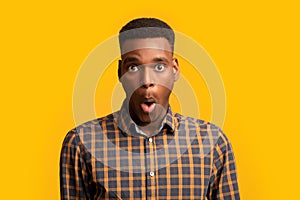 Portrait Of Surprised African American Guy Opened Mouth In Amazement, Yellow Background