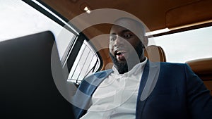 Portrait of surprised african american man getting good news at luxury car.