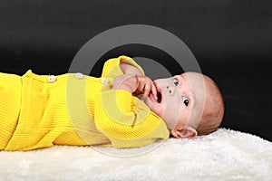 Portrait of surprised baby boy lying on back on white fur