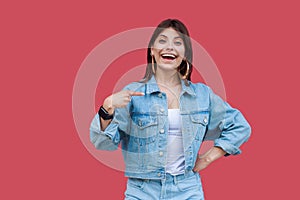 Portrait of surprised beautiful brunette young woman with makeup in denim casual style standing, pointing herself and looking at