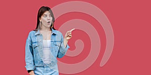 Portrait of surprised beautiful brunette young woman with makeup in denim casual style standing pointing and looking and copyspace