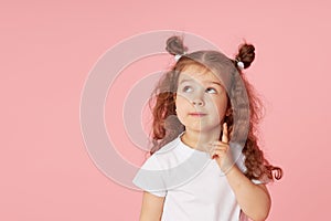 Portrait of surprised cute little toddler girl child over pink background. Looking at camera.