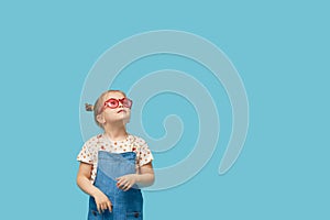 Portrait of surprised cute little toddler girl child standing isolated over blue background.