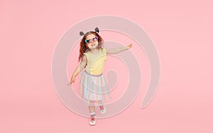 Portrait of surprised cute little toddler girl  in sunglasses over pink background.  Child model