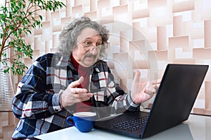 A portrait of a surprised elderly man looking at the computer. A notion of aging and loneliness