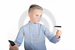 Portrait of a surprised european boy holding mobile phone and credit card. Young man looking at credit card