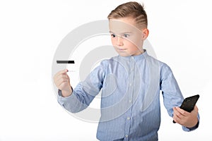 Portrait of a surprised european boy holding mobile phone and credit card. Young man looking at credit card