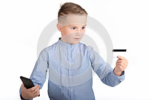 Portrait of a surprised european boy holding mobile phone and credit card. Young man looking at credit card